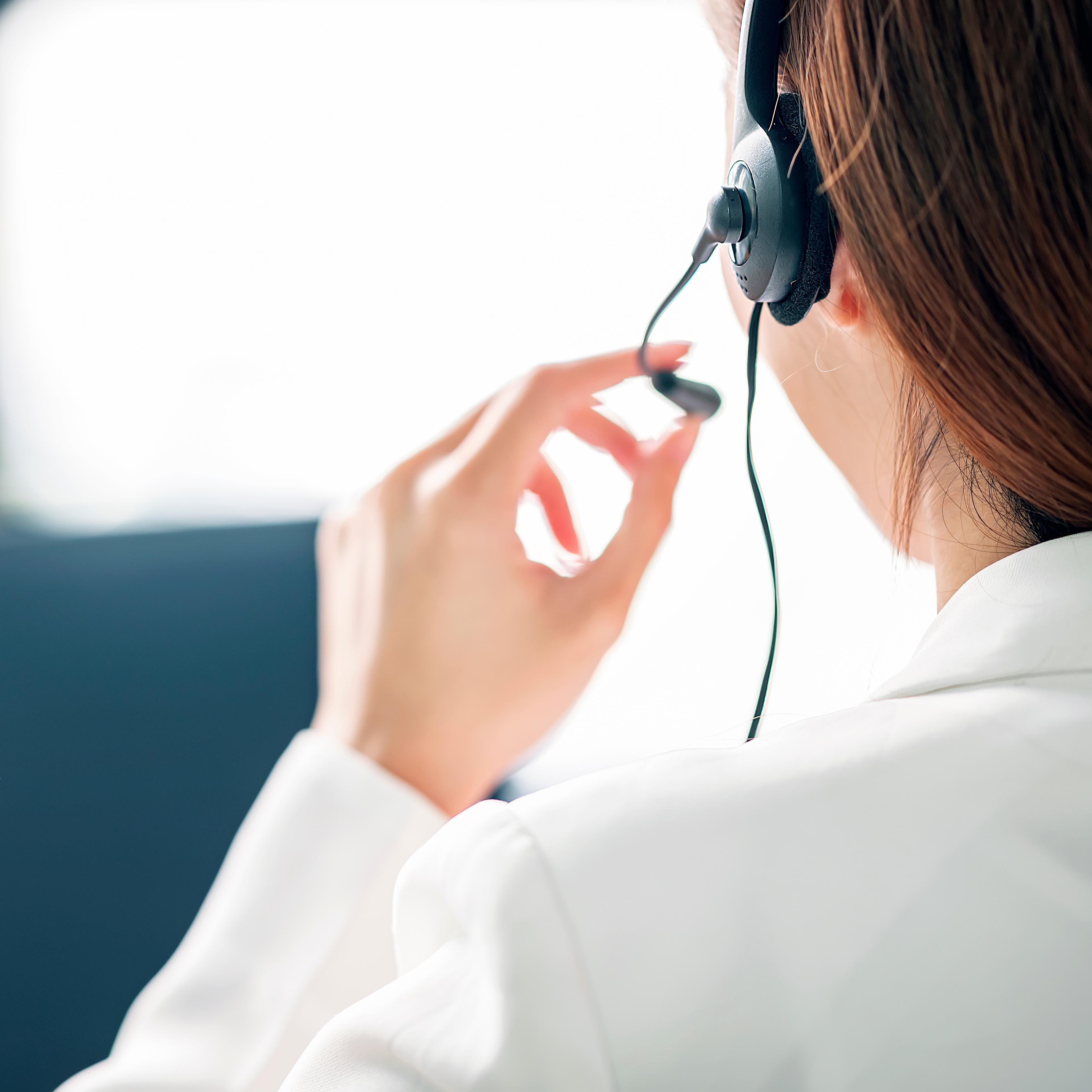 Mitarbeiterin mit Headset in weißem Blazer beim Kundenservice, Fokus auf Kommunikation und Serviceorientierung.