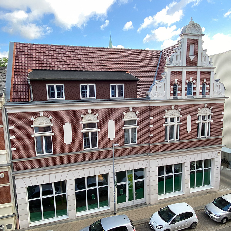 Das Foto zeigt das MIetercenter der WGS. Es handelt sich um ein modernisiertes Altbaugebäude mit rotem Ziegeldach und historischer Fassade sowie großen Fenstern im Erdgeschoss.