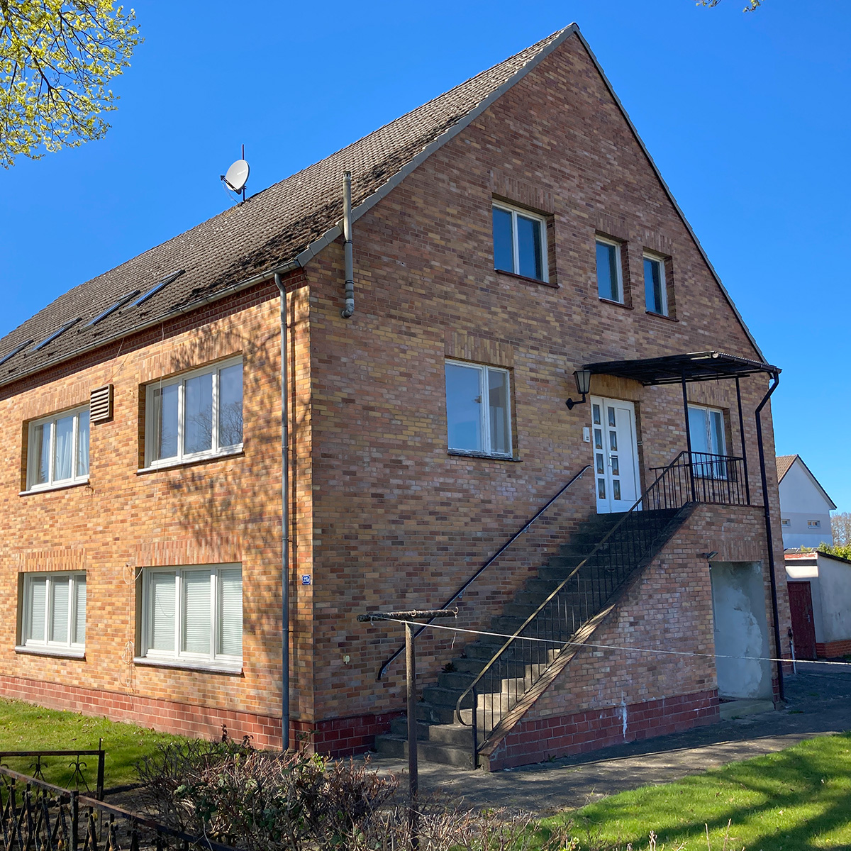 Backstein-Mehrfamilienhaus mit Außentreppe und separatem Hauseingang, freistehend in ruhiger Wohnlage.