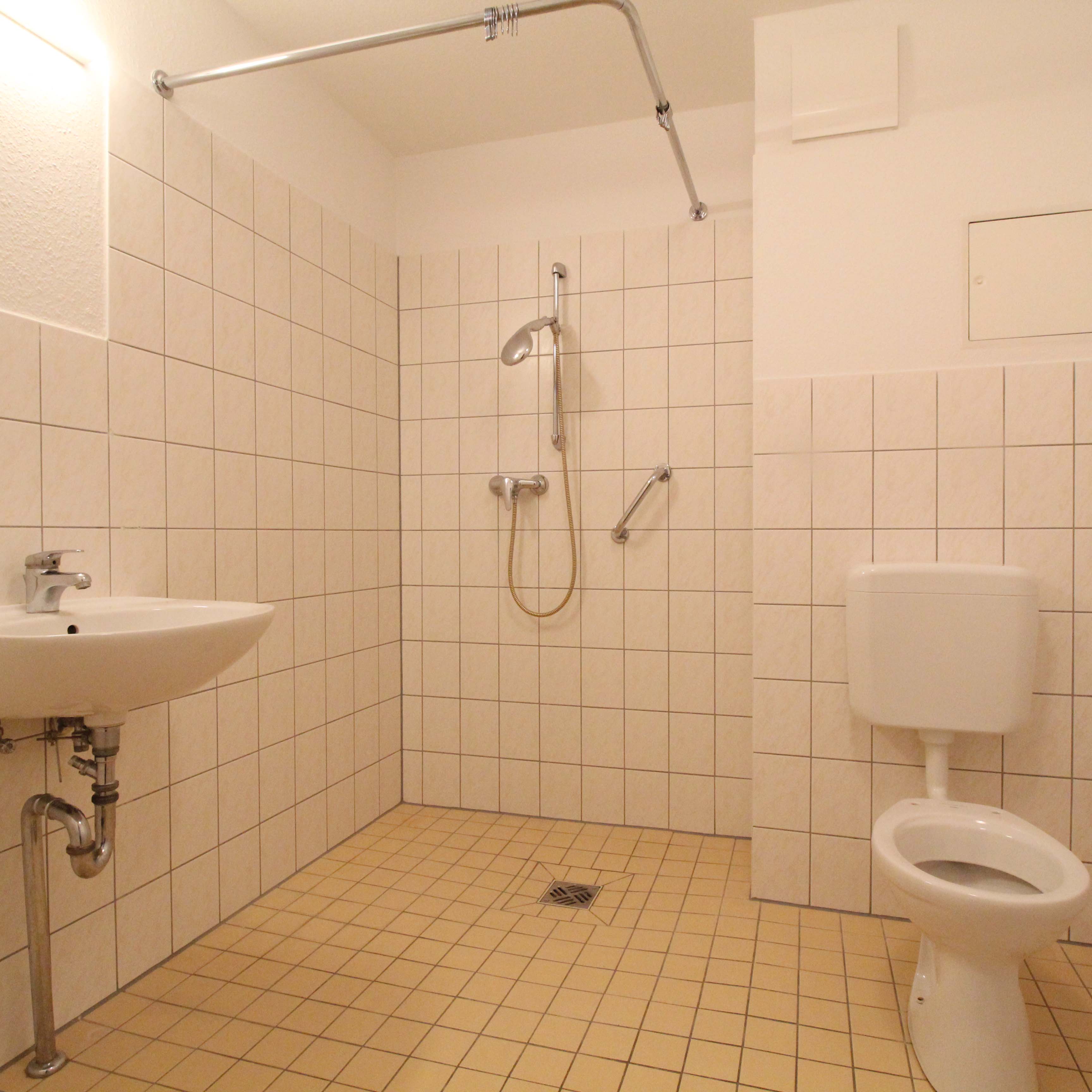 Barrierefreies Badezimmer mit ebenerdiger Dusche und Haltegriff – seniorengerechte Ausstattung