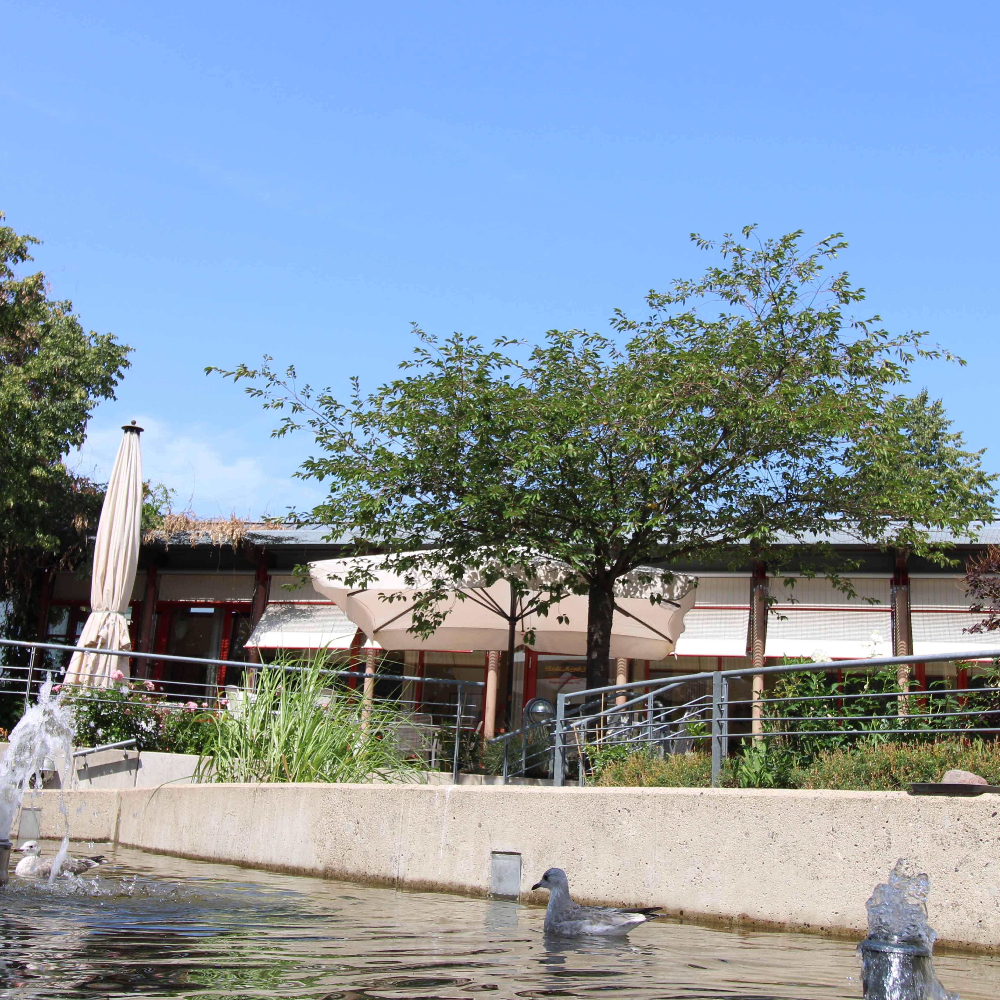 Gemütliche Außenterrasse mit Sonnenschirm und Wasserspiel – ruhiger Sitzbereich im Grünen