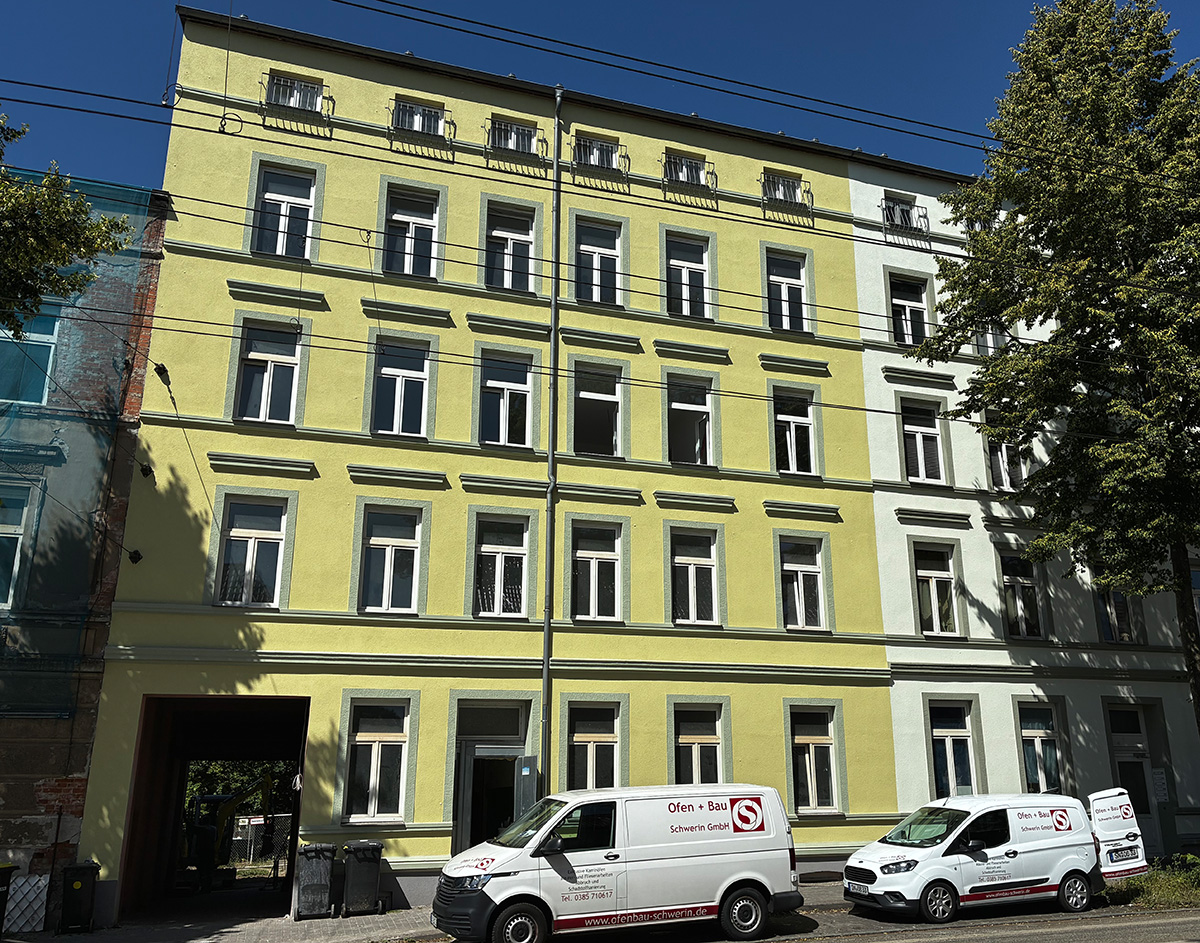 Das modernisierte Wohngebäude mit frischer, grüner Fassade wird geszeigt.